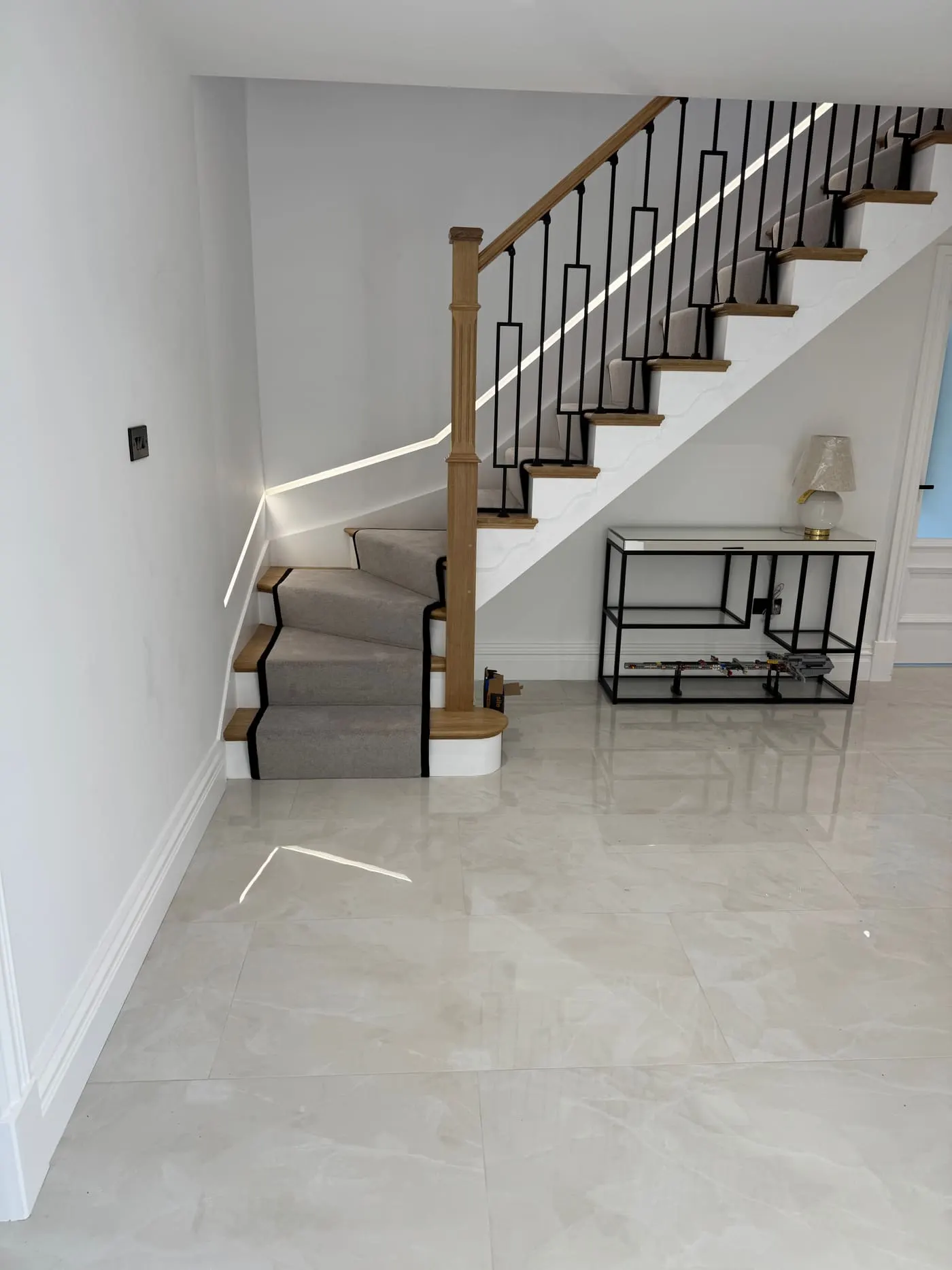 Grey stair runner with black border beside a polished stone hallway floor