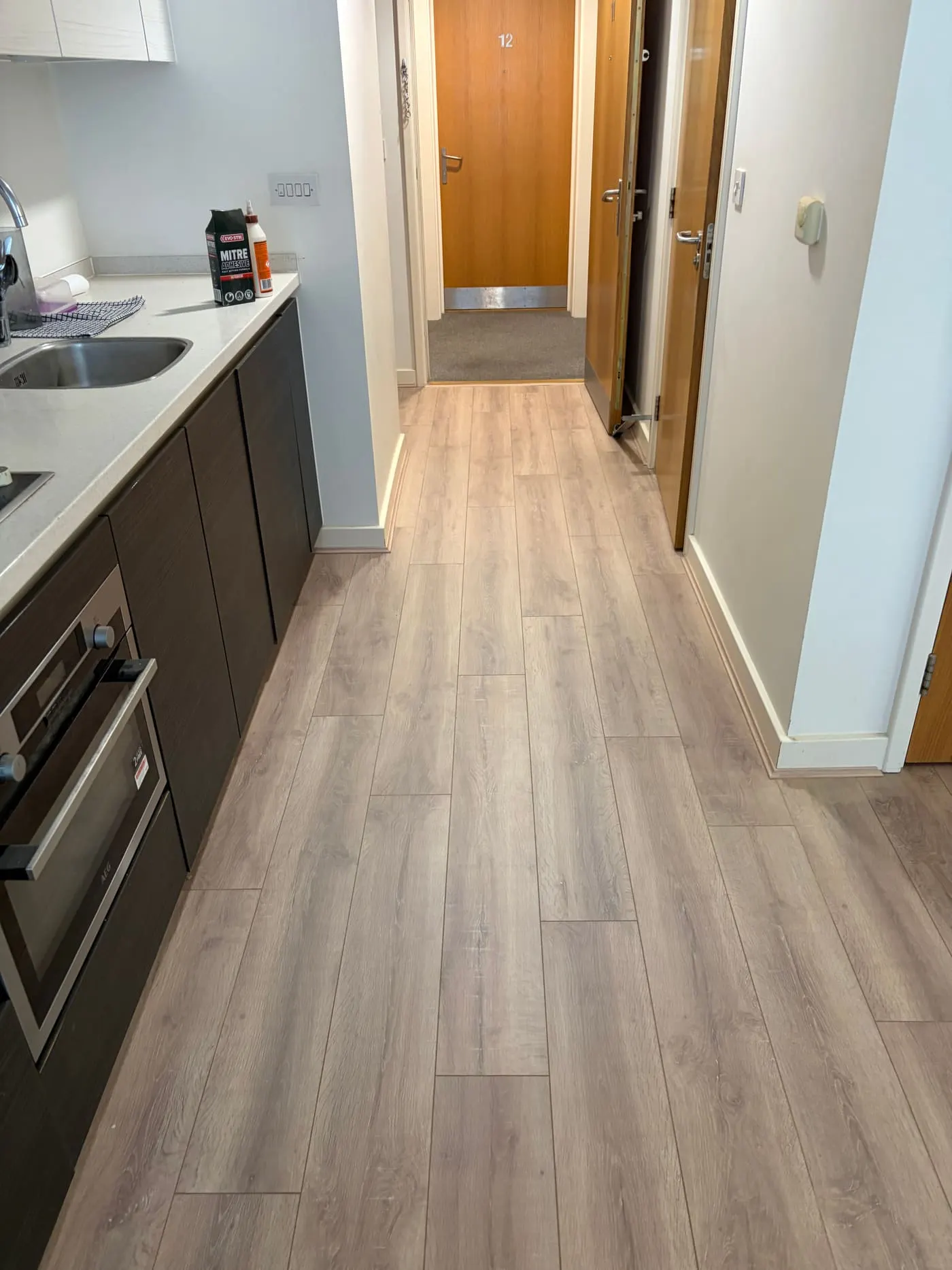 Light oak plank flooring fitted through a kitchen into the hallway